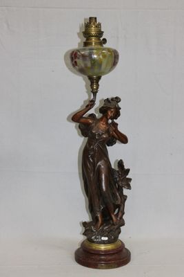 une statue représentant une femme tenant une lampe posée sur une table
