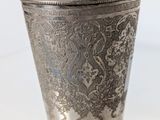 an old silver cup sitting on top of a white table