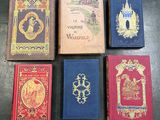 six books are lined up on a table with a castle in the background