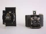 two old cameras are sitting side by side on a white surface