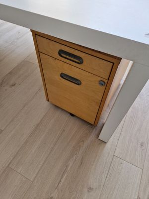 un bureau blanc muni d'un tiroir, posé sur un parquet en bois massif