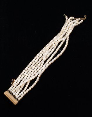 a close up of a necklace with pearls on a black background