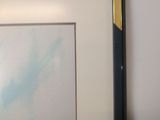 painting of a blue sky with clouds in a black frame on a white wall