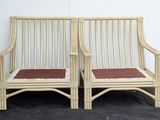 pair of bamboo chairs with red cushions on a black surface