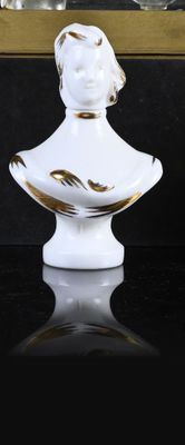 a white and gold bust of a woman sitting on a table