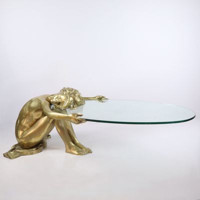 une statue en or représentant une personne tenant une table en verre