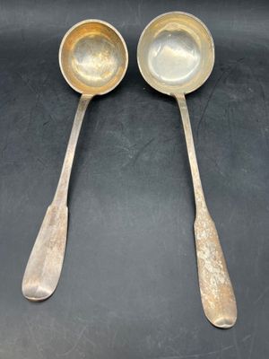 two silver spoons with handles on a black surface