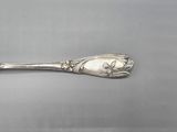 silver spoon with a flower design on it on a gray surface