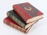 trois vieux livres empilés sur une surface blanche
