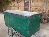 un chariot vert posé à l'intérieur d'une grange au toit en bois