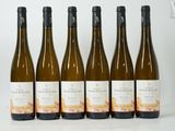 six bottles of white wine are lined up on a table