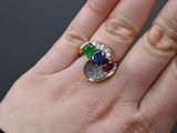 a woman ' s hand holding a ring with a multicolored stone