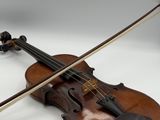 an old violin sitting on top of a white table next to a bow