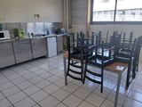 tables and chairs in a kitchen with a refrigerator in the background