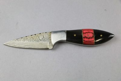 a knife with a red handle on a white surface