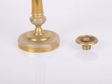 a gold candle that is next to a brass candle holder