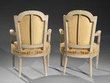 pair of carved chairs with upholstered backrests and arms