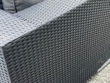 grey wicker outdoor sofa with cushions on a gravel patio