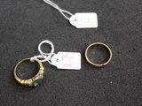 deux bagues en or et une bague en argent, avec une étiquette de prix, posées sur un fond noir
