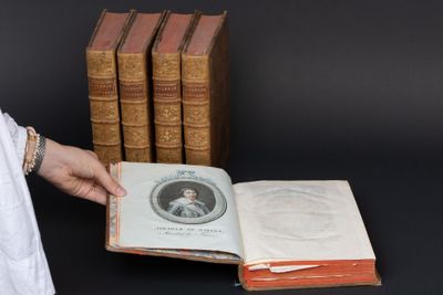 une personne tenant un livre devant une pile de livres
