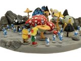 figurines représentant un groupe de Schtroumpfs rassemblés autour d'un champignon posé sur un rocher
