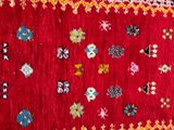 a close up of a red rug on a grey floor