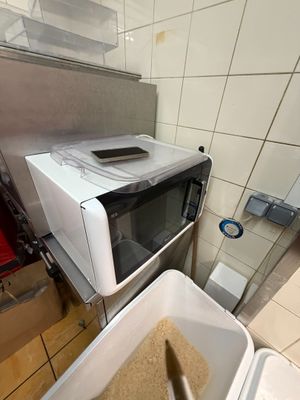 a white microwave sitting on top of a counter next to a trash can