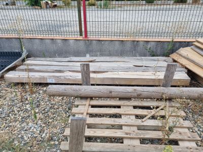 un tas de palettes en bois posé par terre près d'une clôture