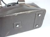 a brown leather bag with a handle on a white surface