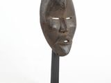 an image of a wooden mask on a black stand on a white background