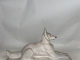 a statue of a dog laying down on a white background