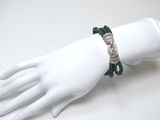 une main de mannequin blanche à laquelle est attaché un bracelet vert