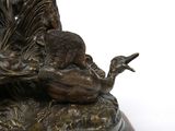 a bronze statue of a bird and a bird sitting on a rock