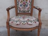 an old chair with a floral upholstered back and arms