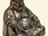 a small statue of a smiling buddha sitting on a pillow