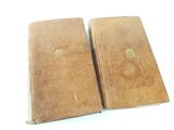 two old books sitting on top of each other on a white surface