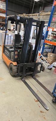 un chariot élévateur dans un entrepôt rempli de palettes et de cartons