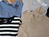 a lot of sweaters that are on a bed