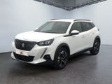 La voiture blanche est garée dans une grande pièce au sol noir.