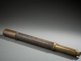 un vieux télescope en laiton dans un coffret en bois, posé sur une surface grise