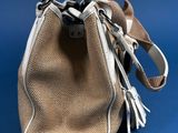 beige and white purse with a leather handle on a blue background