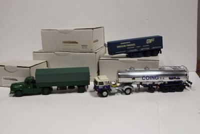 Plusieurs camions miniatures sont alignés les uns à côté des autres sur une surface blanche
