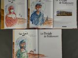 three books with pictures of people in hats on them on a table