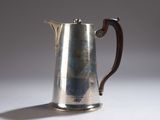 une cafetière en argent avec un manche en bois sur une table