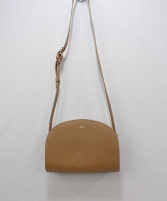 a tan leather purse hanging on a white wall