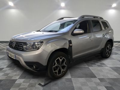 La Dacia argentée est garée dans une pièce au sol carrelé en damier.