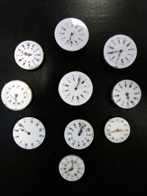 neuf horloges posées sur une table noire, sur fond noir