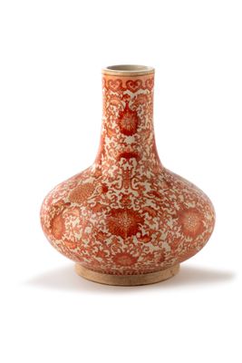 un vase rouge et blanc posé sur une surface blanche
