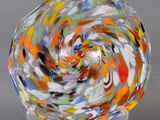 une image représentant un bol en verre multicolore posé sur un socle