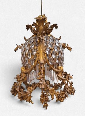 un lustre de couleur dorée auquel est suspendue une abat-jour en verre